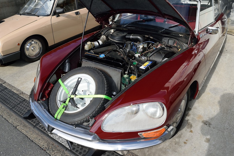 巨大なボンネットを開くと、ハイドロの油圧系統が張り巡らされ、他車とは少し様相が異なるエンジンルーム。DSをご覧になった方なら、これかなり手入れの行き届いた状態なのがお分かりいただけるかと・・・ちなみにスペアタイヤはこんなところにあるんです。なんで熱々になるボンネット内に置くのかは置いておいて（笑）