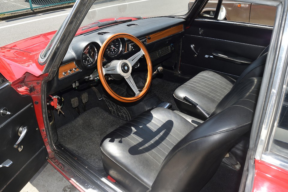 黒基調の中で、ひと際目立つダッシュの横一線の木目パネル。オリジナルの華奢な2本スポークステアリングから換装されたナルディのウッドハンドルとの相性もバッチリ！