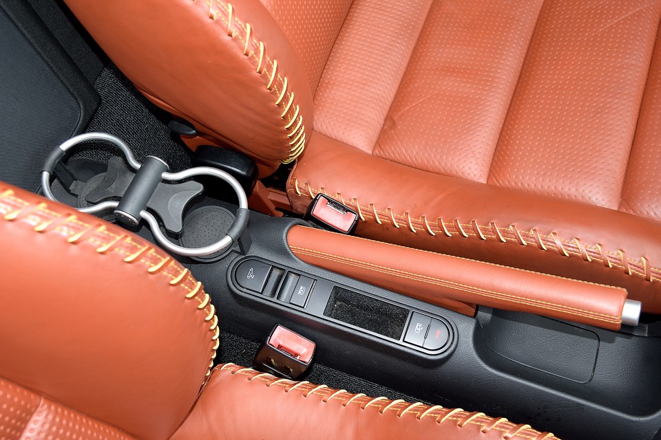 この年代になると欧州車にもちゃんとドリンクホルダーが装備されます。パーキングブレーキ横にはドアロックスイッチ、幌の電動開閉スイッチ、そして座席背面のウインドリフレクター（風の巻込防止パネル）の上下スイッチがあります。